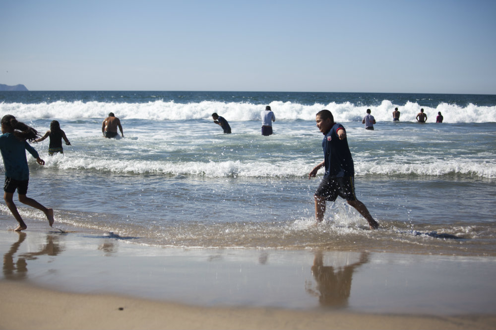 Migrant adults and children whooped and splashed around at Playas De Tijuana, located right next to the border fence on Wednesday, November 14, 2018. Erin Siegal McIntyre/KQED