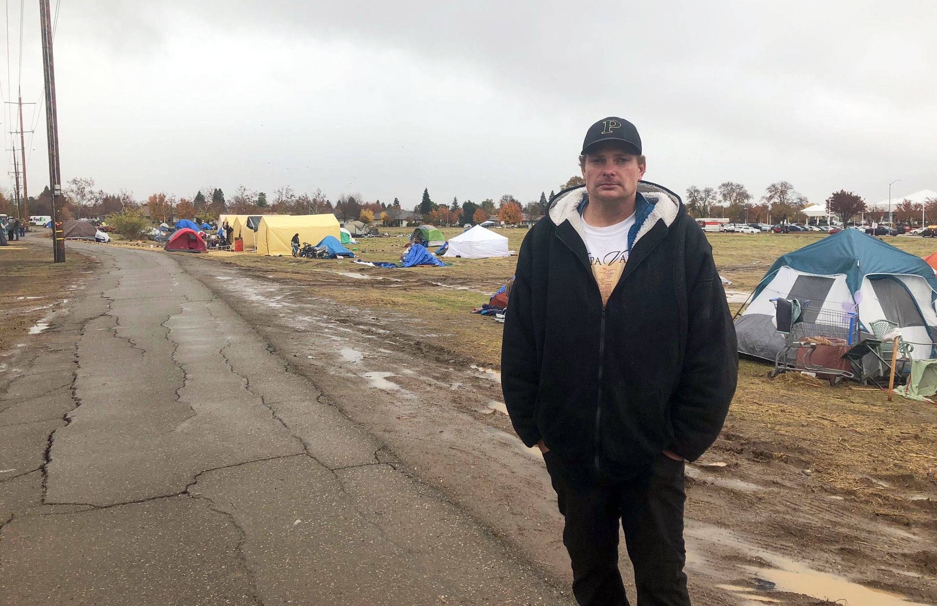Ulis Gordon stands by several dozen tents outside a Chico Walmart where some Camp Fire survivors are staying. Sonja Hutson/KQED