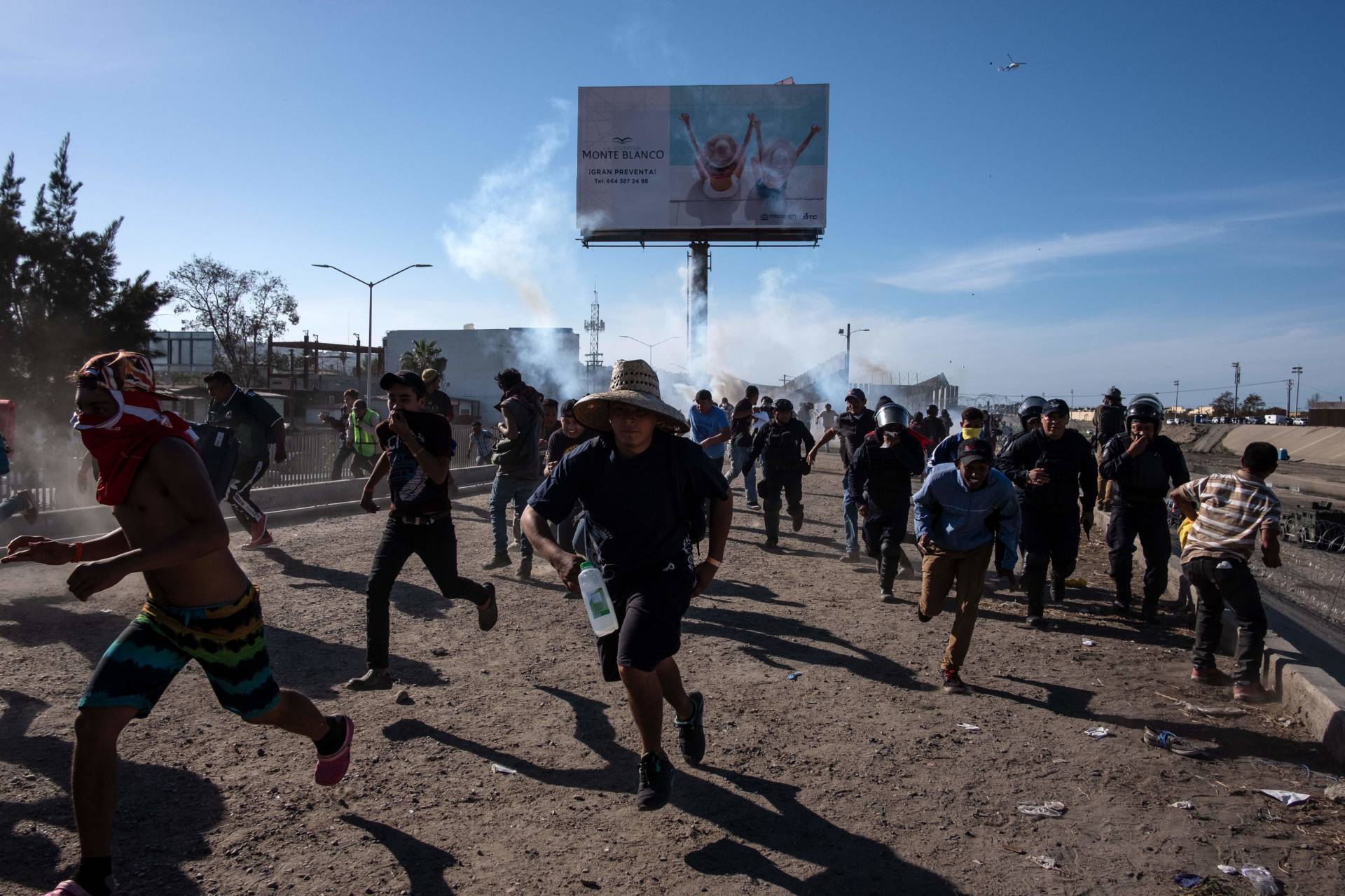 Central American migrants, mostly Hondurans, run along the Tijuana River near the El Chaparral border crossing after U.S. border agents threw tear gas from a distance to disperse them after an alleged verbal dispute on Nov. 25, 2018. Guillermo Arias/AFP/Getty Images