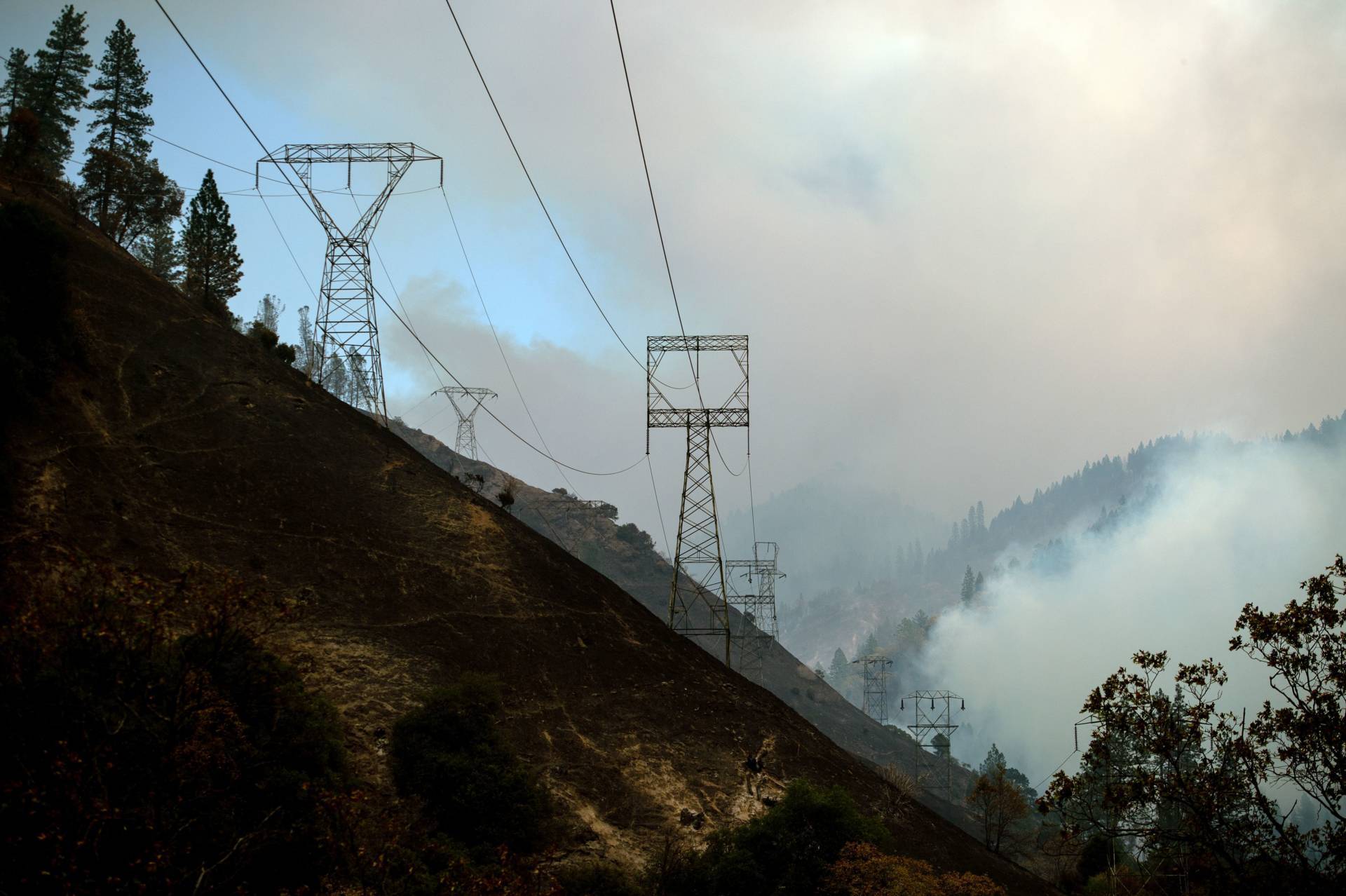 PG&amp;E transmission  towers on the Caribou-Palermo line are seen against a smoky landscape adjacent to the Feather River in Butte County last November. The towers are close to the spot where officials say the Camp Fire began. Josh Edelson/AFP-Getty Images