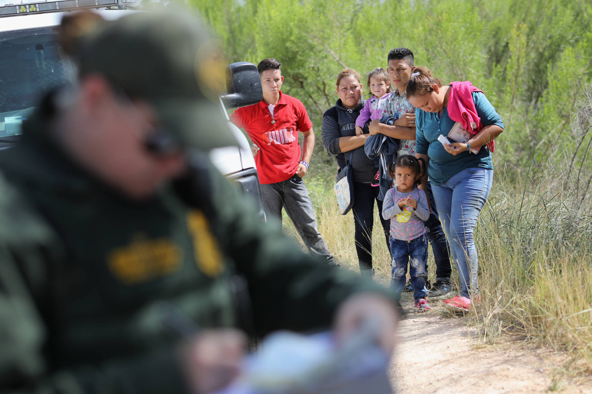 Central American asylum-seekers wait as U.S. Border Patrol agents take groups of them into custody on June 12, 2018, near McAllen, Texas. The families were then sent to a U.S. Customs and Border Protection processing center for possible separation.  John Moore/Getty Images