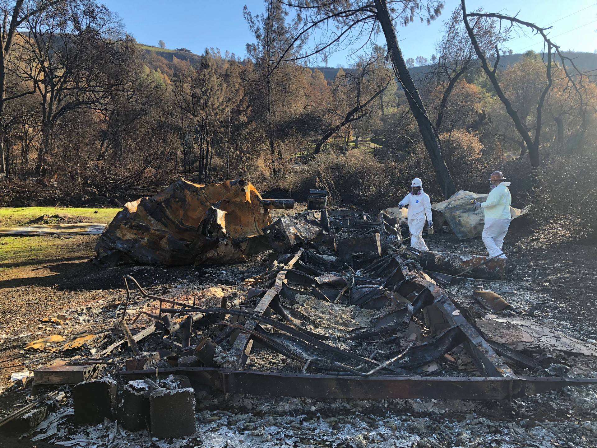 EPA workers use a radiation detector and multi-gas meter to search for hazardous waste in a mobile home destroyed by the Camp Fire. Sonja Hutson/KQED