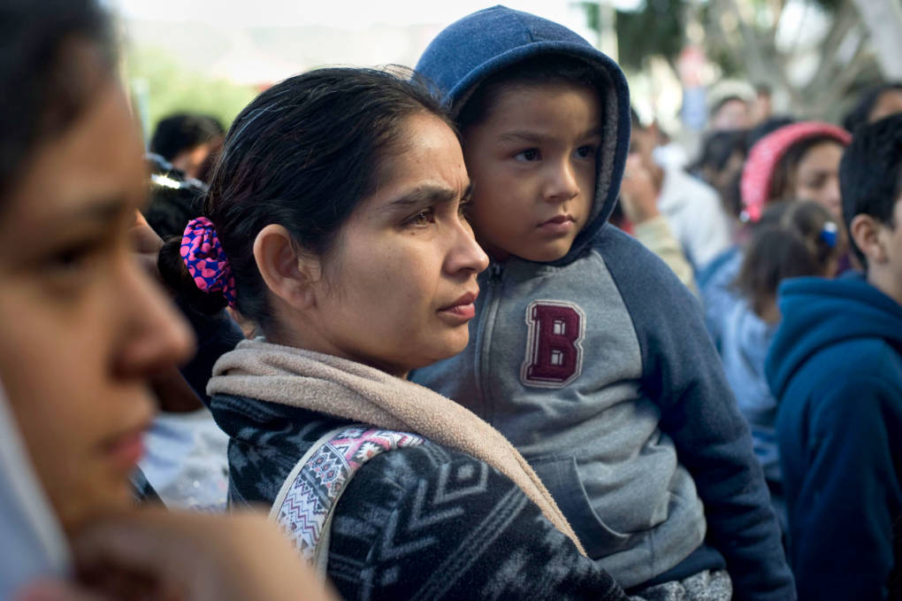 A woman and child wait to hear their position on a list of asylum-seekers waiting at the U.S.-Mexico border on Nov. 21, 2018.  David Maung/KQED