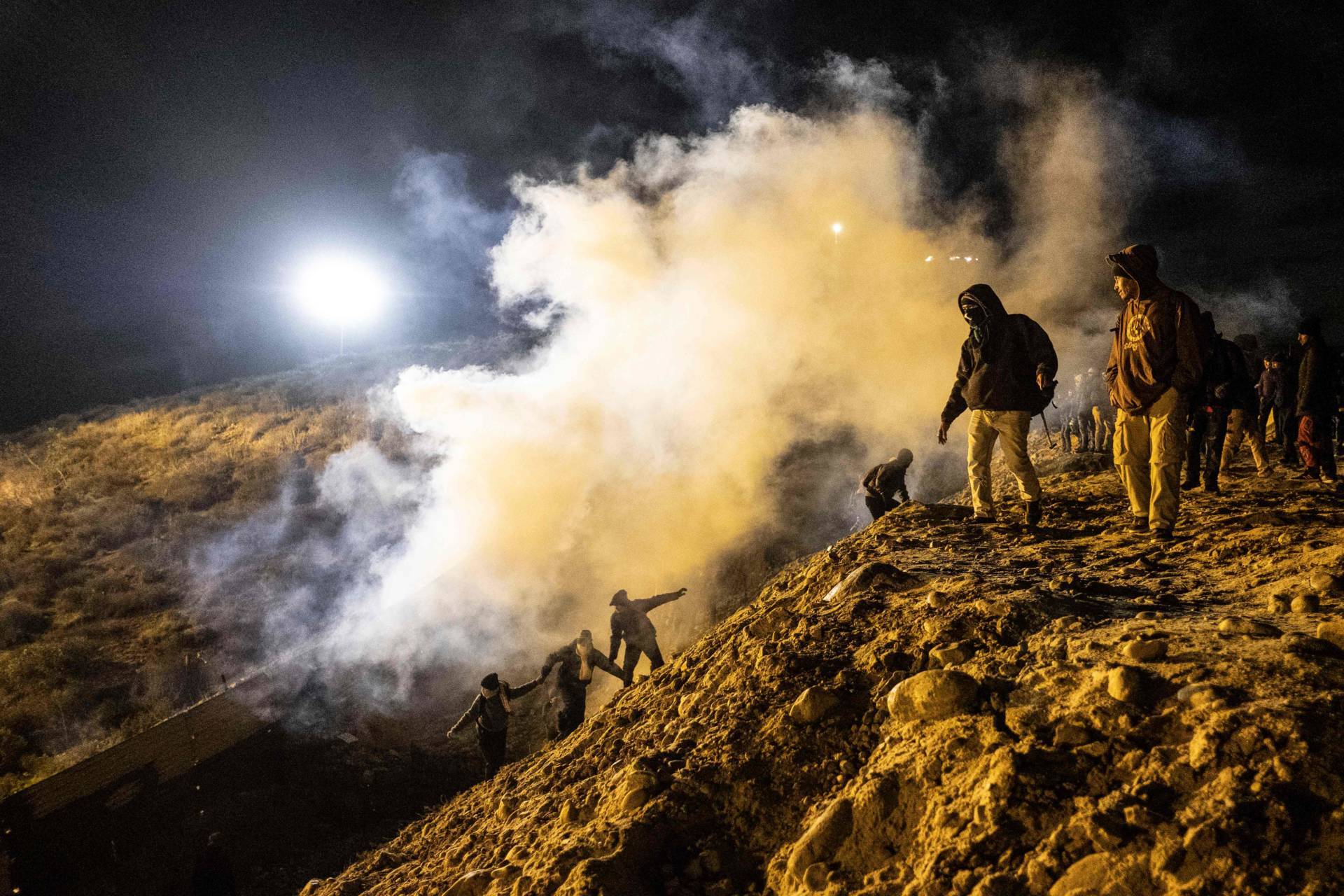 Central American migrants run away from tear gas thrown by the US border patrol, after they tried to cross from Tijuana to San Diego in the U.S., as seen from Tijuana, Mexico on January 1, 2019. Guillermo Arias/AFP/Getty Images)