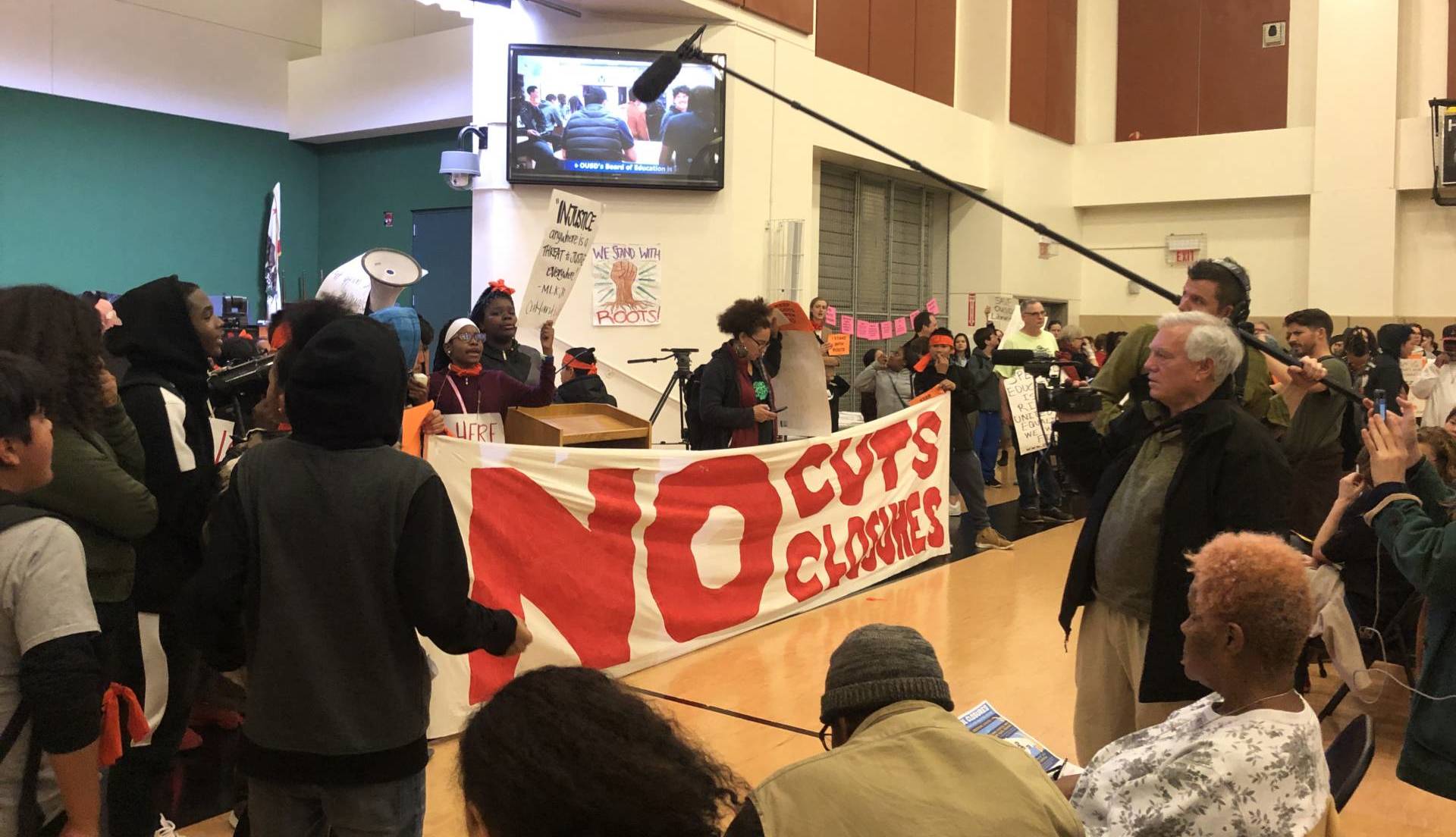 Demonstrators at an OUSD board meeting on Jan. 23, 2019, at La Escuelita Elementary School voiced their opposition to the district's proposal to close Roots International Academy, a small middle school in East Oakland. Julia McEvoy/KQED