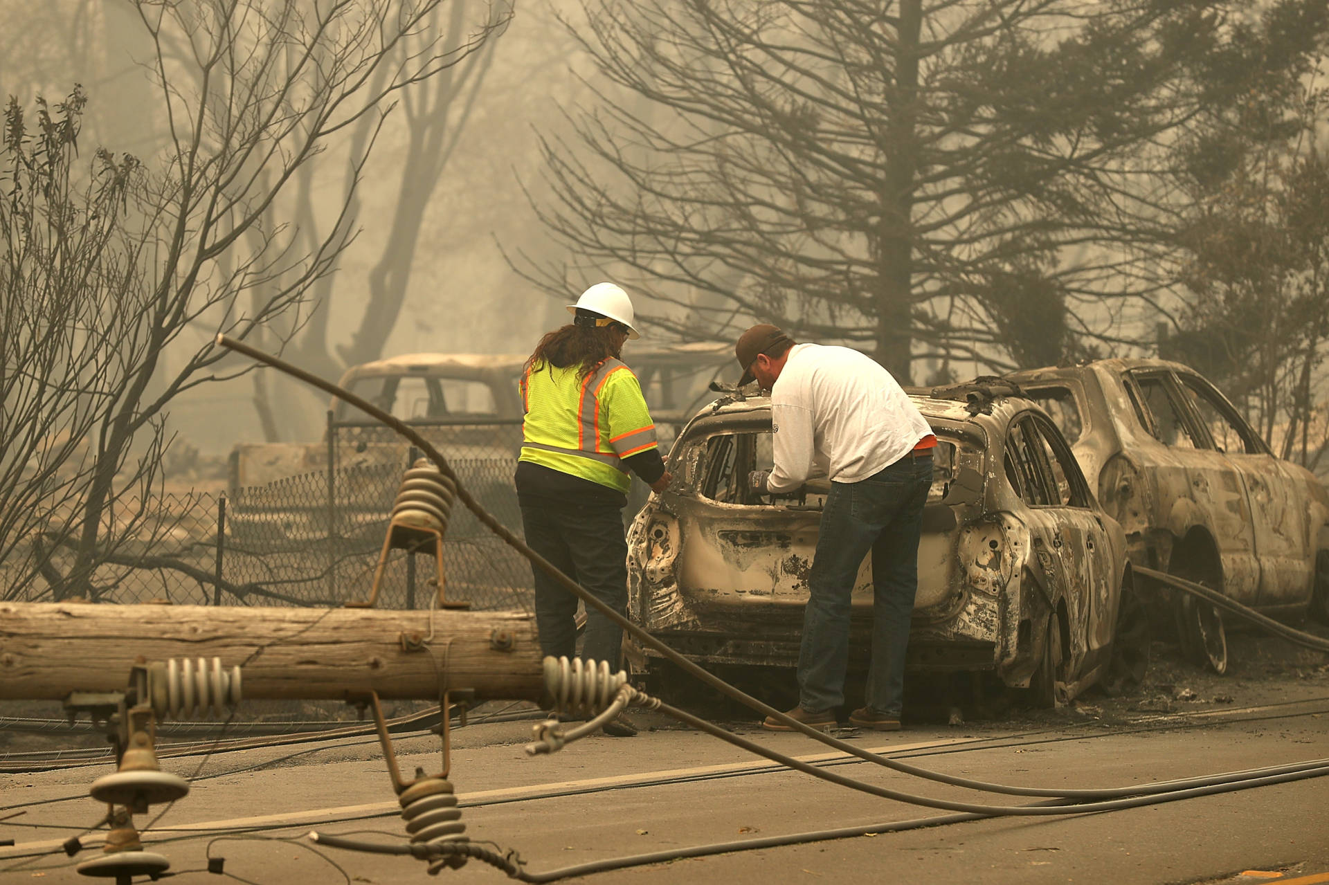 Eric England (R) looks through his friend's car that was burned by the Camp Fire on November 10, 2018, in Paradise, California. Before the filing, PG&amp;E sought to assure the public that it would continue making safety investments in an attempt to avoid future catastrophic wildfires. Justin Sullivan/Getty Images
