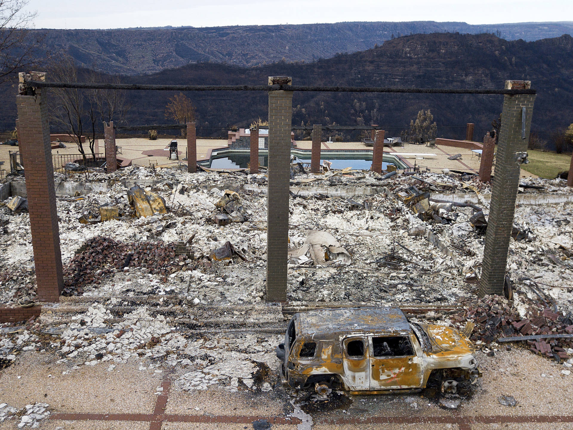 A vehicle rests in front of a home leveled by the Camp Fire in Paradise, in a photo from December. Pacific Gas &amp; Electric has said it's 'probable' investigators will conclude its equipment ignited the November 2018 catastrophe. Noah Berger/AP