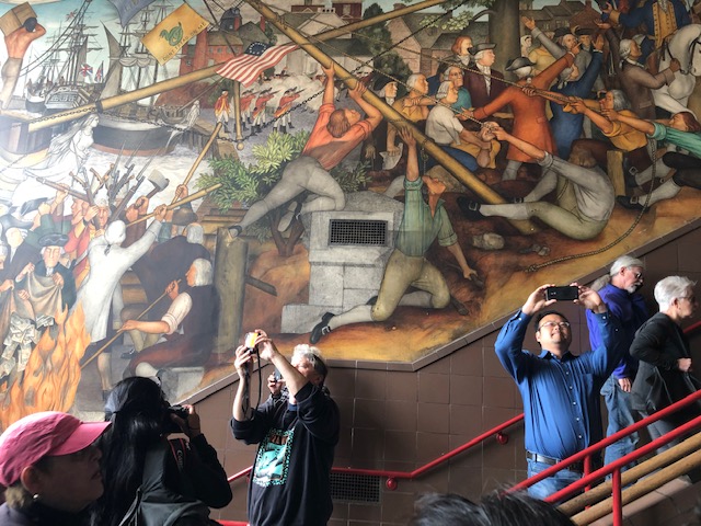 People take photos of a mural.