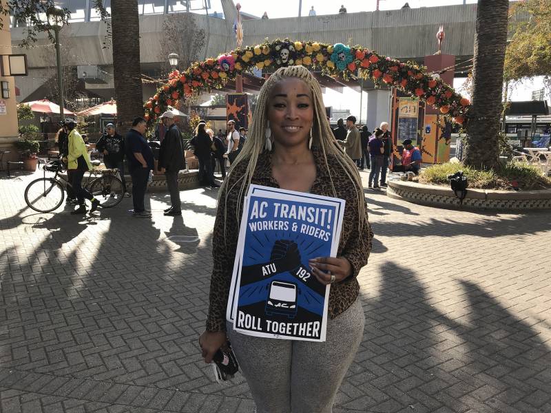 Karen Hopper, who has been driving with AC Transit for 17 years, is standing while holding up a sign that reads "AC Transit! Workers & riders roll together". She attended a rally hosted by ATU Local 192 which was held at Fruitvale BART station in Oakland on Saturday, November 16, 2019.