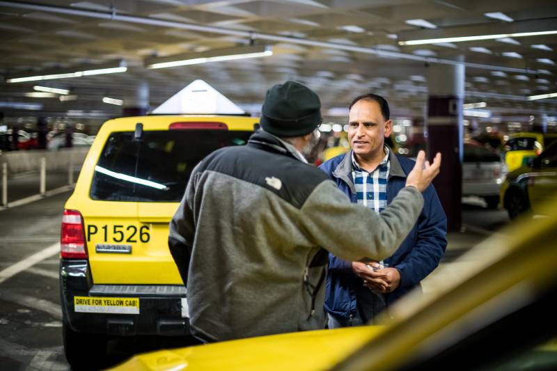 Taxi drivers Ali Asghar (L) and Namdev Sharma (R) talk while they wait for a fare at San Francisco International Airport on Jan. 30, 2020.