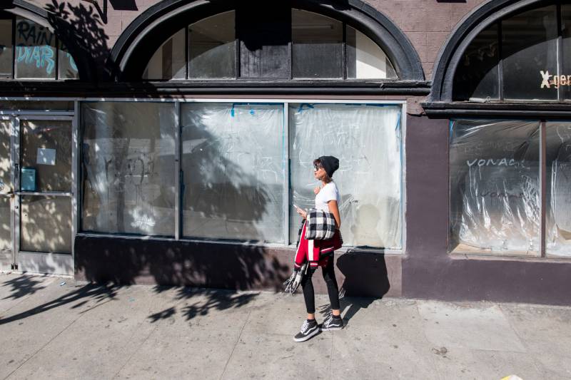 A woman walks past a series of empty Upper Haight storefronts in San Francisco on Tuesday, Feb. 25, 2020. The store on the left was previously occupied by Kids Only, which closed in 2016. The store on the right housed X Generation, which closed in 2017.