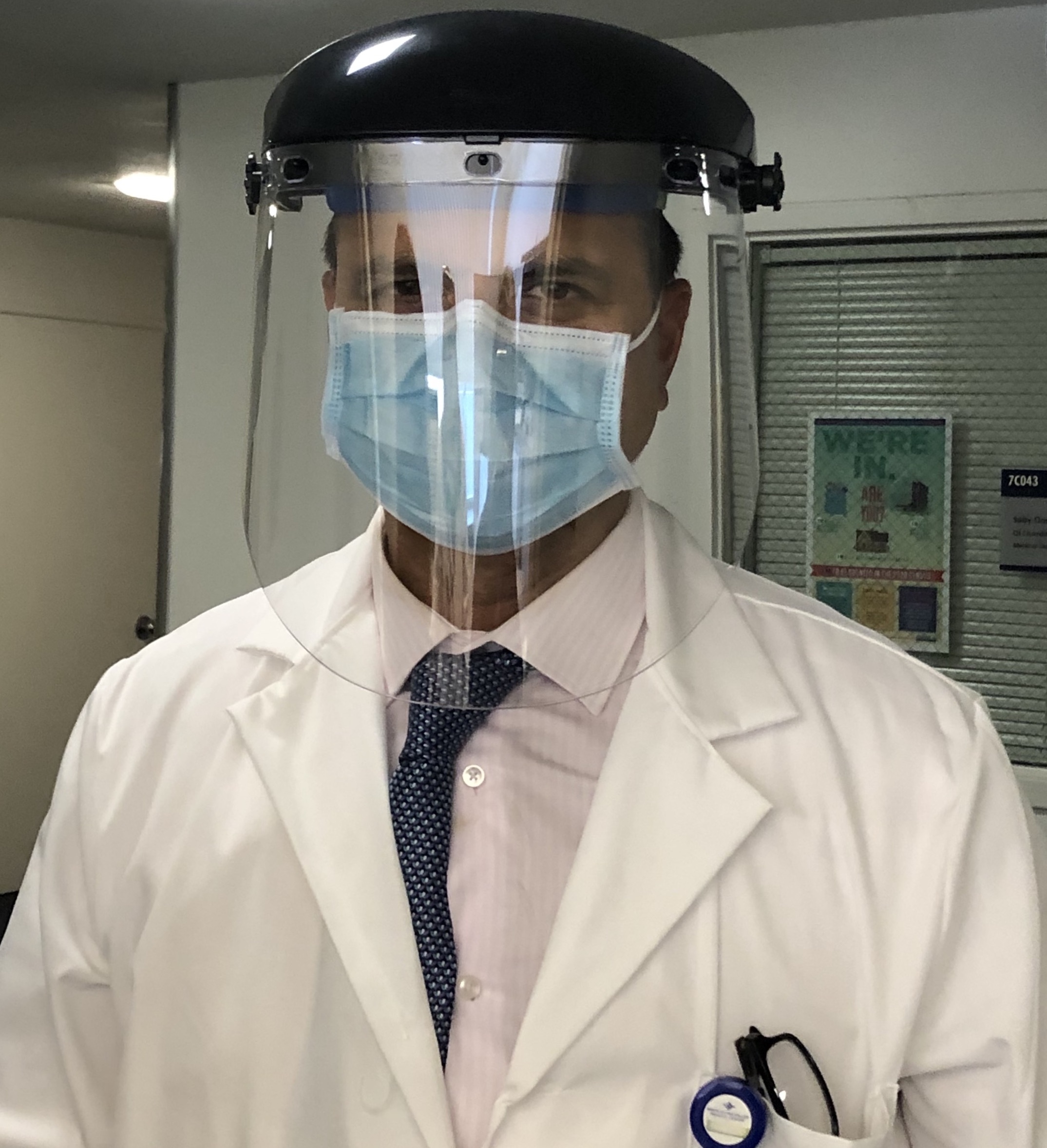 Dr. Sanjay Kurani, hospital medical director at the Santa Clara Valley Medical Center, models a plastic face shield worn over a surgical mask. 