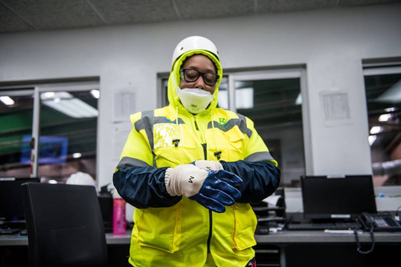 Recology employee and union shop steward Ayanna Banks puts on three layers of gloves before going to work on a sorting line at Recology's processing facility in San Francisco on April 9, 2020.