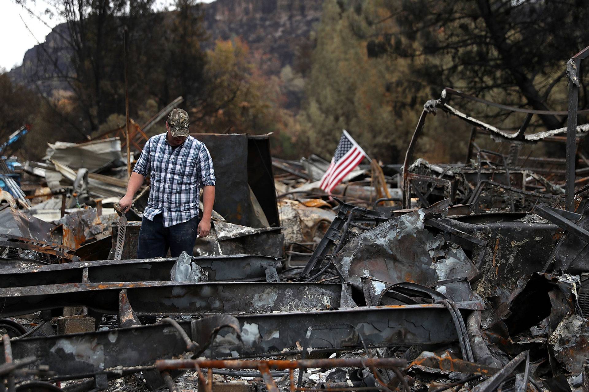 A man looks over his burned home, destroyed by the Camp Fire in Nov. 2018 in Paradise. The deadline for 70,000 survivors of numerous fires to vote on a multi-billion-dollar settlement deal with PG&E was May 15. Justin Sullivan/KQED