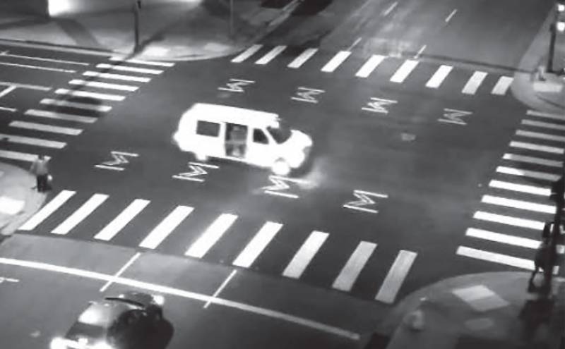A black and white aerial photo of a white van in a crosswalk.