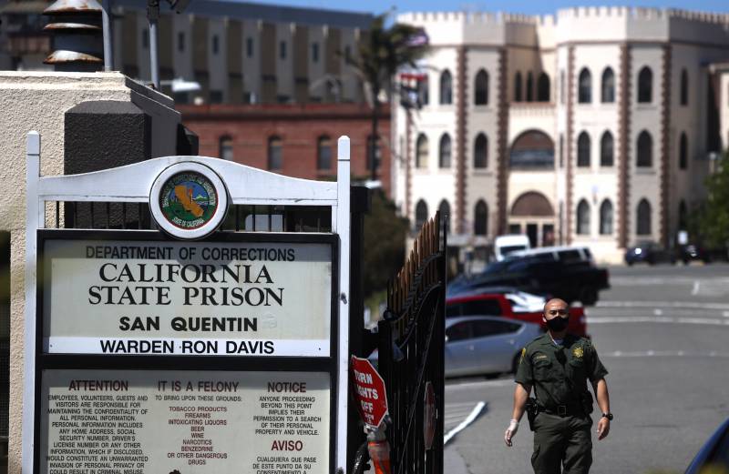 A man stands with a mask at the entrance to San Quentin State Prison.