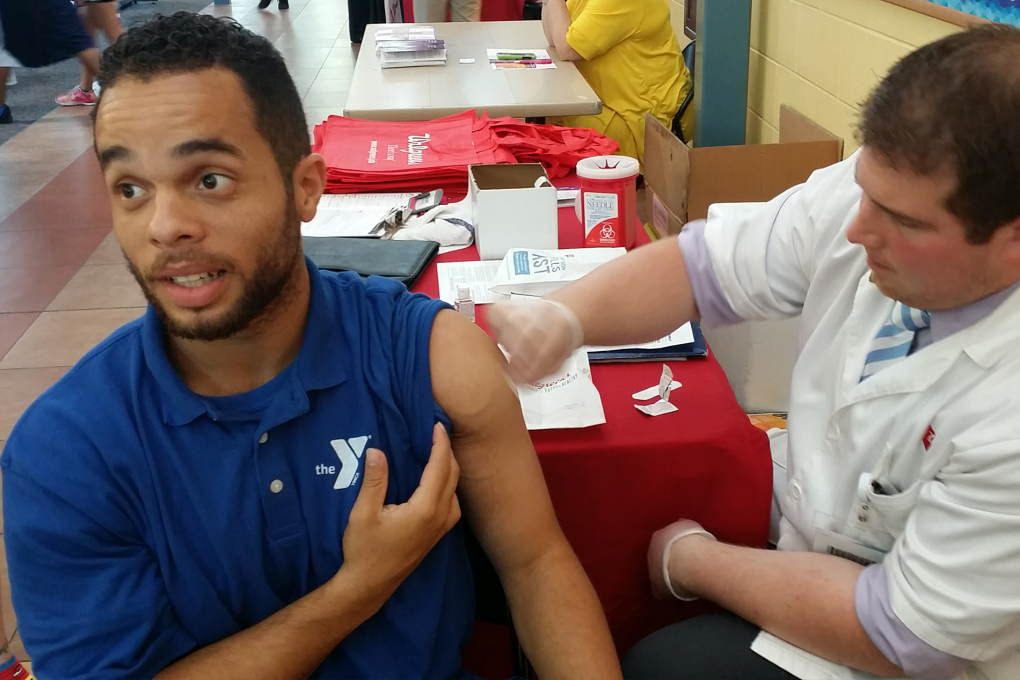 A person is seated receiving their flu shot from a medical professional