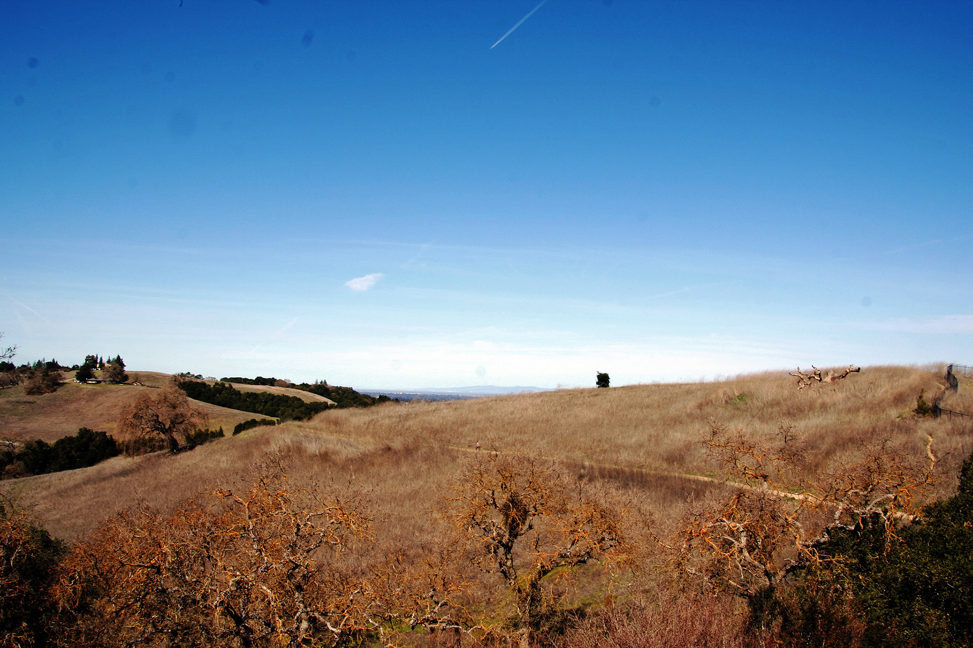 Brown, grassy hillsides under blue skies.