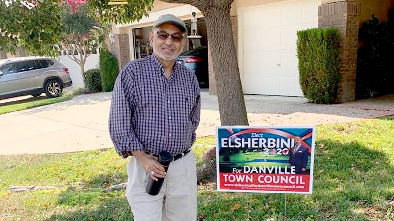 Muhammed Jawaid, an immigrant from Pakistan, poses in front of his Danville home by a yard sign supporting his friend Mohamed Elsherbini's campaign for Danville town council.