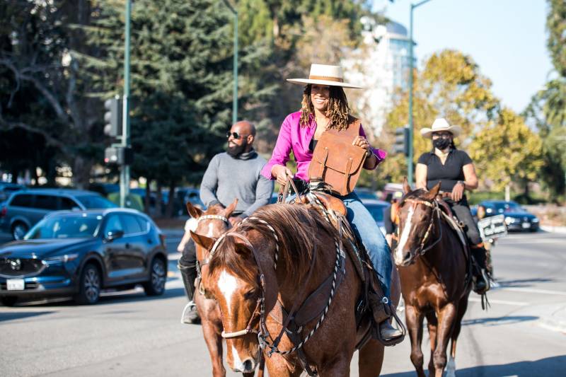 Brianna Noble (front), Dale Johnson (L) and Rachel Royce (R) ride their horses to the Alameda County Courthouse in Oakland to drop off their mail-in ballots as part of a Ride Out to Vote event on Oct. 29, 2020.