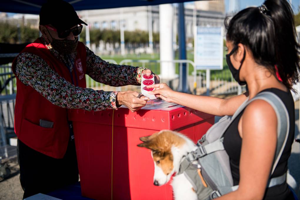 A voter receives an "I Voted" sticker at a new outdoor voting center near Civic Center Plaza in San Francisco on Oct. 5, 2020, the first day of early voting.
