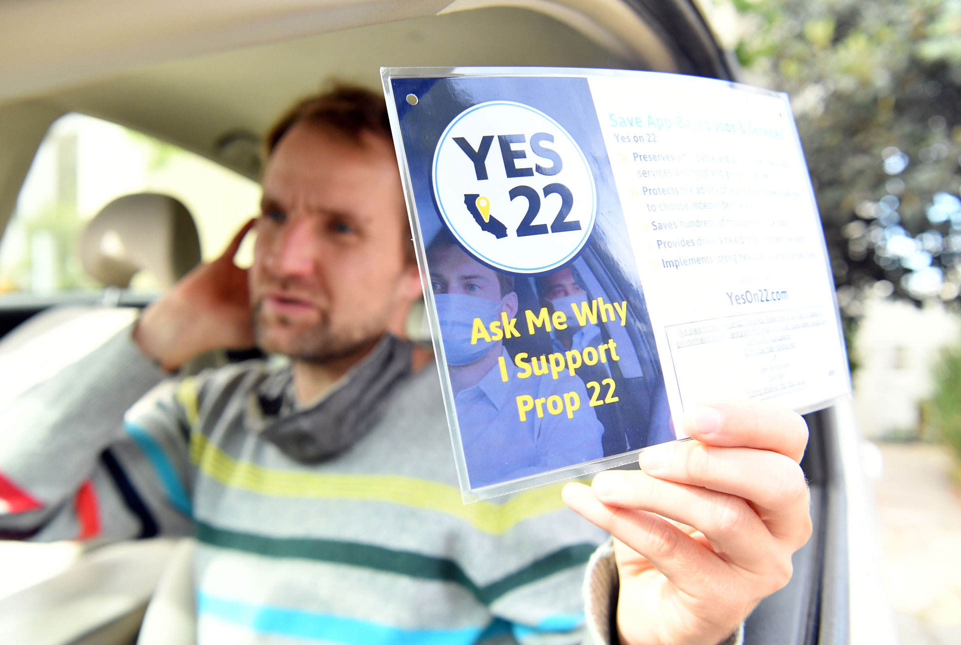 Uber driver Sergei Fyodorov holds a flyer supporting a yes vote on Proposition 22 in Oakland.