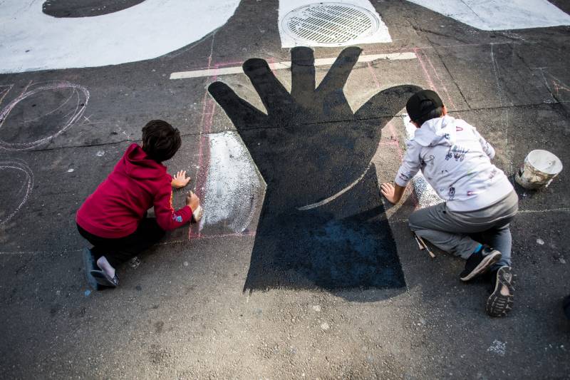 Two children help paint a part of a street mural that reads "Hands Off Our Ballots" on Montgomery Street in San Francisco on Nov. 6, 2020.