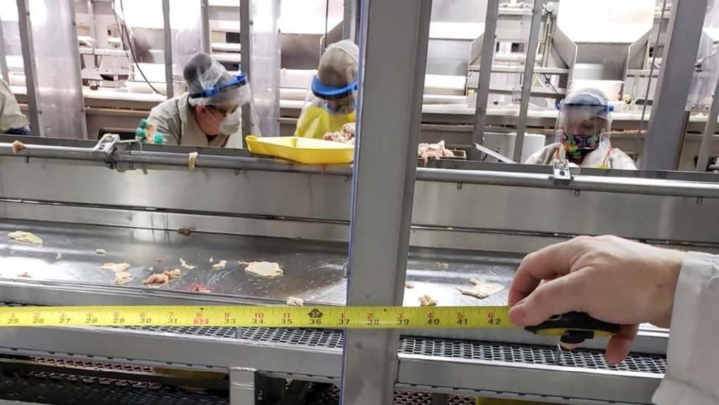 Workers standing near each other at a Foster Farms assembly line in Livingston.