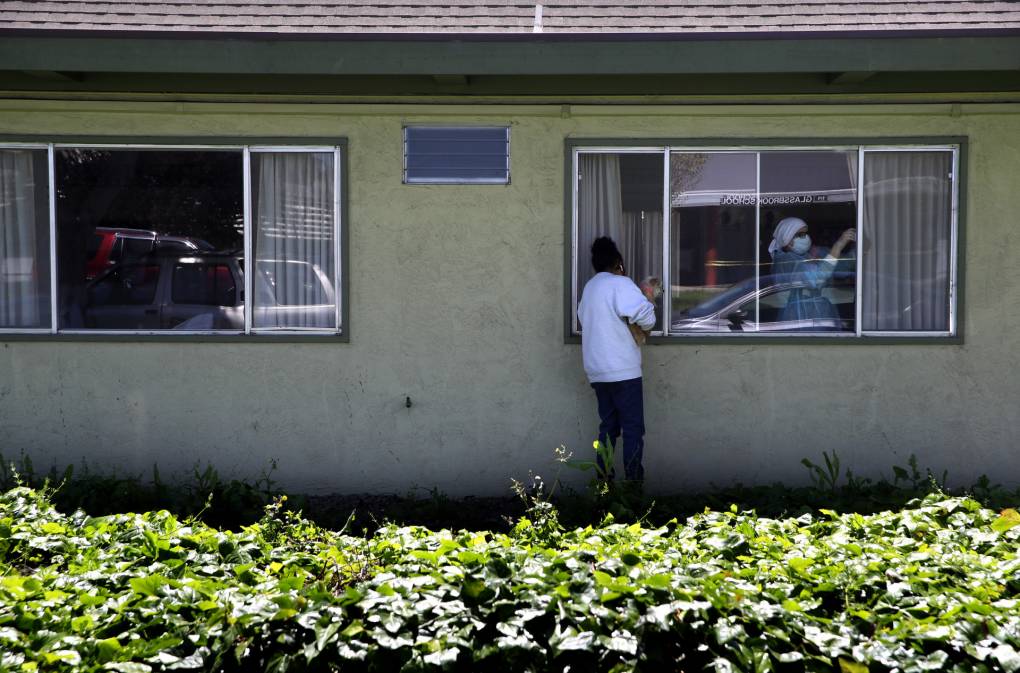HAYWARD, CALIFORNIA - APRIL 14: Adrina Rodriguez holds her dog as she looks through a window while visiting her father who is a patient at the Gateway Care and Rehabilitation Center that has tested negative for COVID-19 on April 14, 2020 in Hayward, California. The Gateway Care and Rehabilitation Center remains open after a tenth patient died from COVID-19 complications.