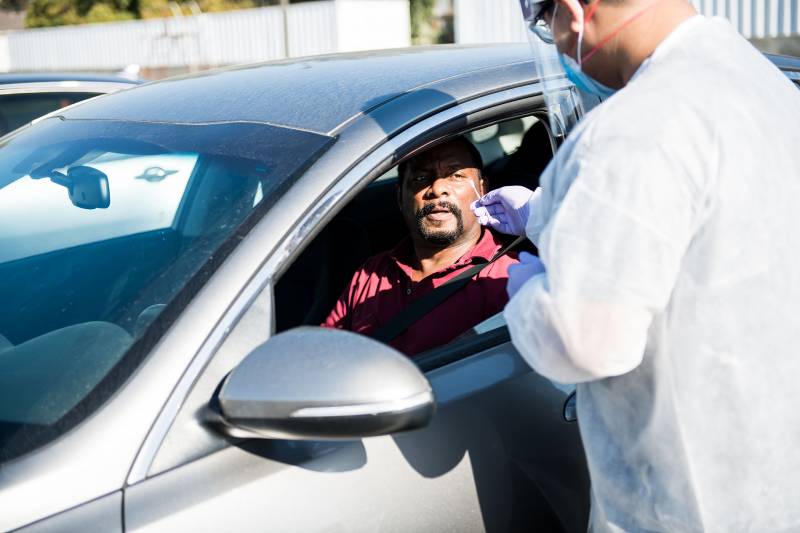 Phlebotomy tech Brandon Tran administers a COVID-19 swab test to Herb Sanders in his car at a COVID-19 testing pop-up site by Umoja hosted by Acts Full Gospel Church in Oakland on Oct. 31, 2020. Umoja's mission was to get more African Americans in Oakland to get tested for the coronavirus as well as to present a more accurate picture of positivity rates in the Black population.