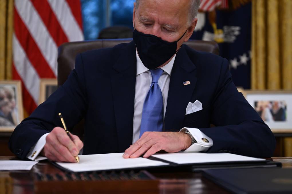 Joe Biden signs orders at the resolute desk in the Oval Office