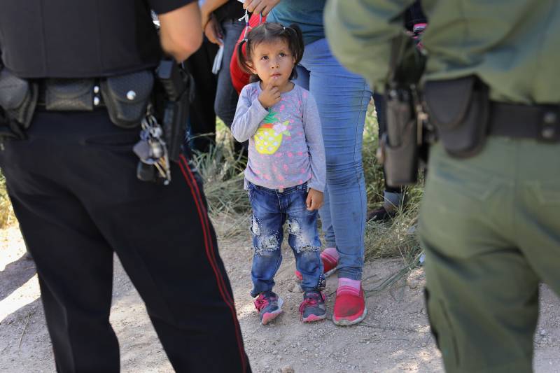 child looks up at CBP agents