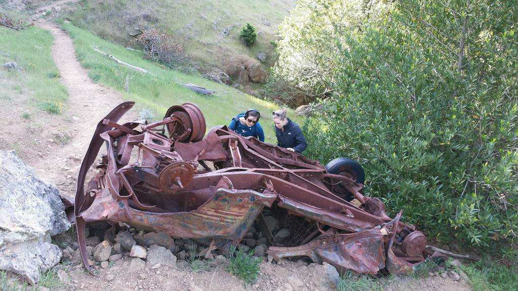 Katrina and Olivia investigate the wreck of a vintage car on a hiking trail in Marin.