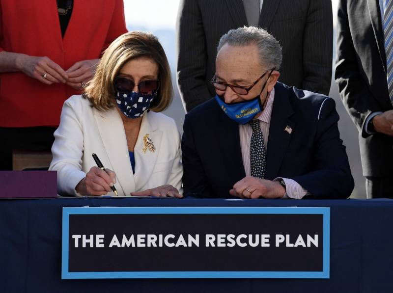 Pelosi and Schumer sitting with masks on, signing American Rescue Plan Act