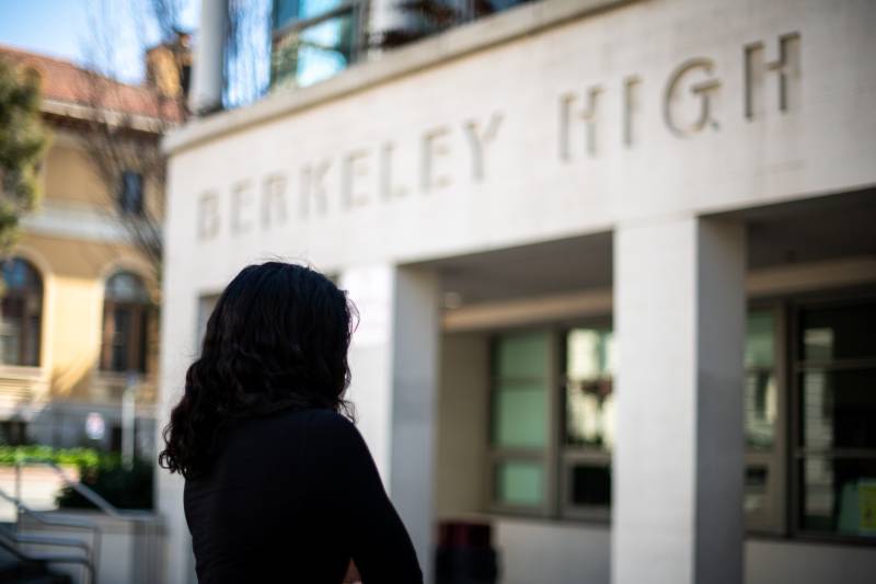 Anonymous Berkeley High student known as 'Faith' standing in front of the high school, back turned