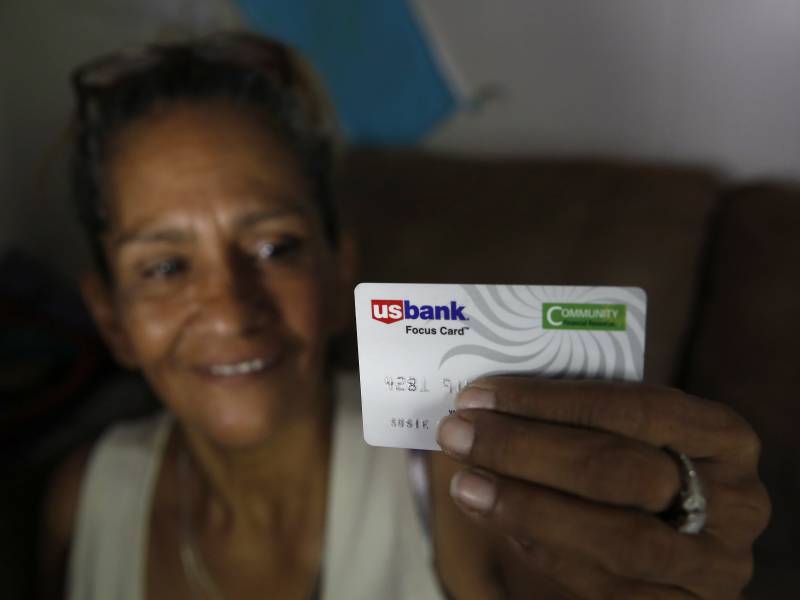 woman UBI recipient smiling, holding debit card