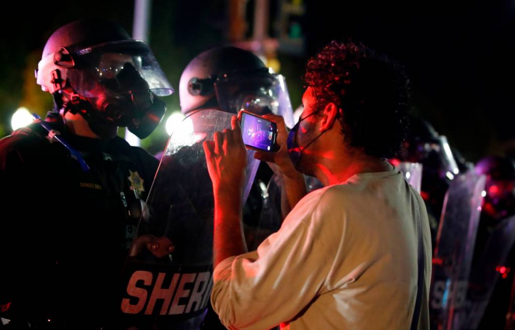A protester records a video on his cellphone as he faces off with law enforcement outside the County Courthouse during demonstrations against the shooting of Jacob Blake in Kenosha, Wisconsin, on Aug. 25, 2020. Kamil Krzaczynski/AFP via Getty Images