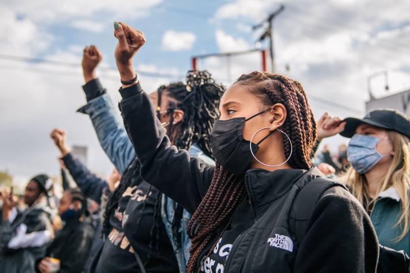 Black women wearing masks, fists raised in solidarity
