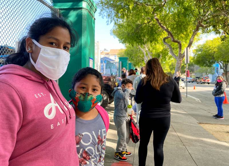 Mom and daughter wearing masks outside school