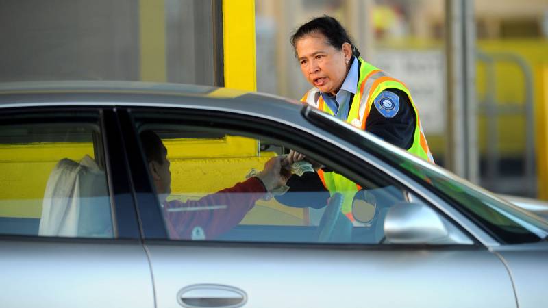 A toll worker taking cash from a driver.