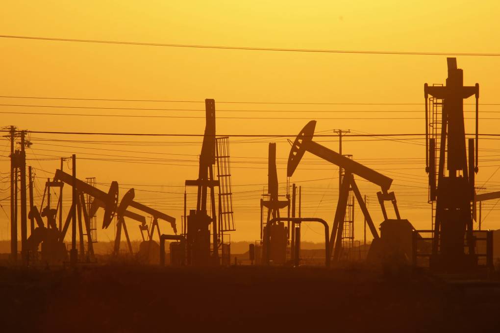 Pump jacks draw oil in a field over the Monterey Shale formation ear Lost Hills, California in 2014. It is the late afternoon and the sky is painted a fierce orange.