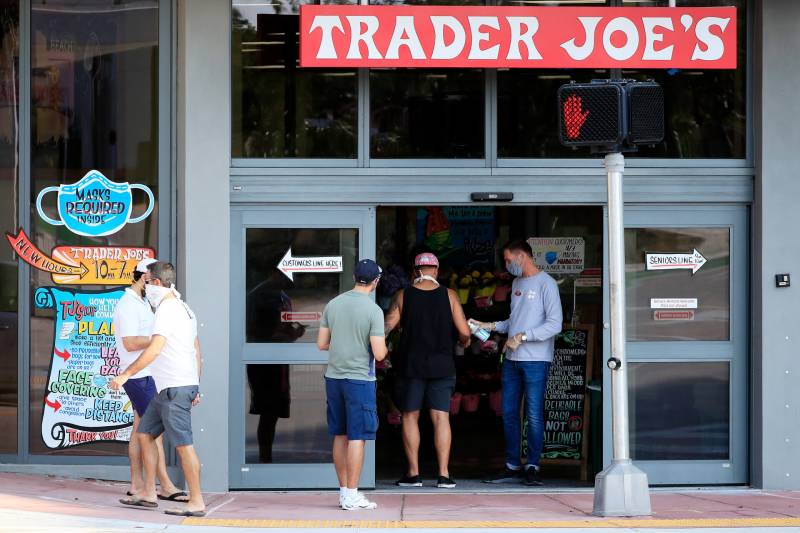 A worker distributes hand sanitizer to customers at a Trader Joe's store. Until June 15, masks will still be required inside stores in California, including national chains like Starbucks, Walmart and Trader Joe's.