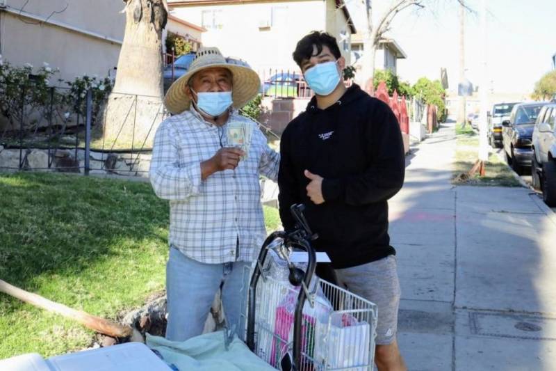 Una imagen de Jesús Morales, influencer de TikTok, y un vendedor ambulante. El vendedor lleva puesto un sombrero para protegerse del sol y en sus manos unos billetes que Morales le dio.