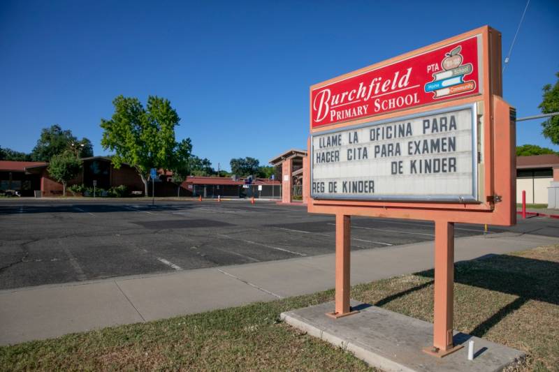 The Burchfield primary school marquee written in Spanish and English informing parents to call the school office to make a kindergarten entrance exam appointment in Colusa.