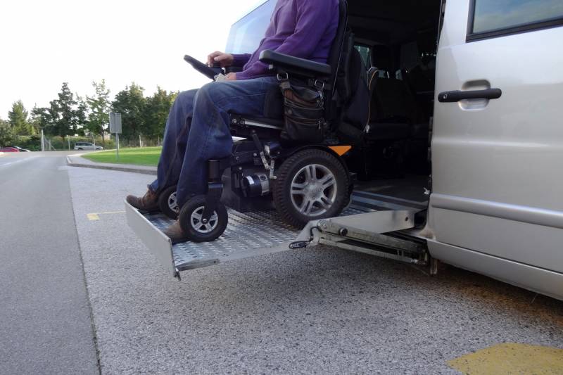Man on motorized wheelchair on a lift on a wheelchair accessible vehicle