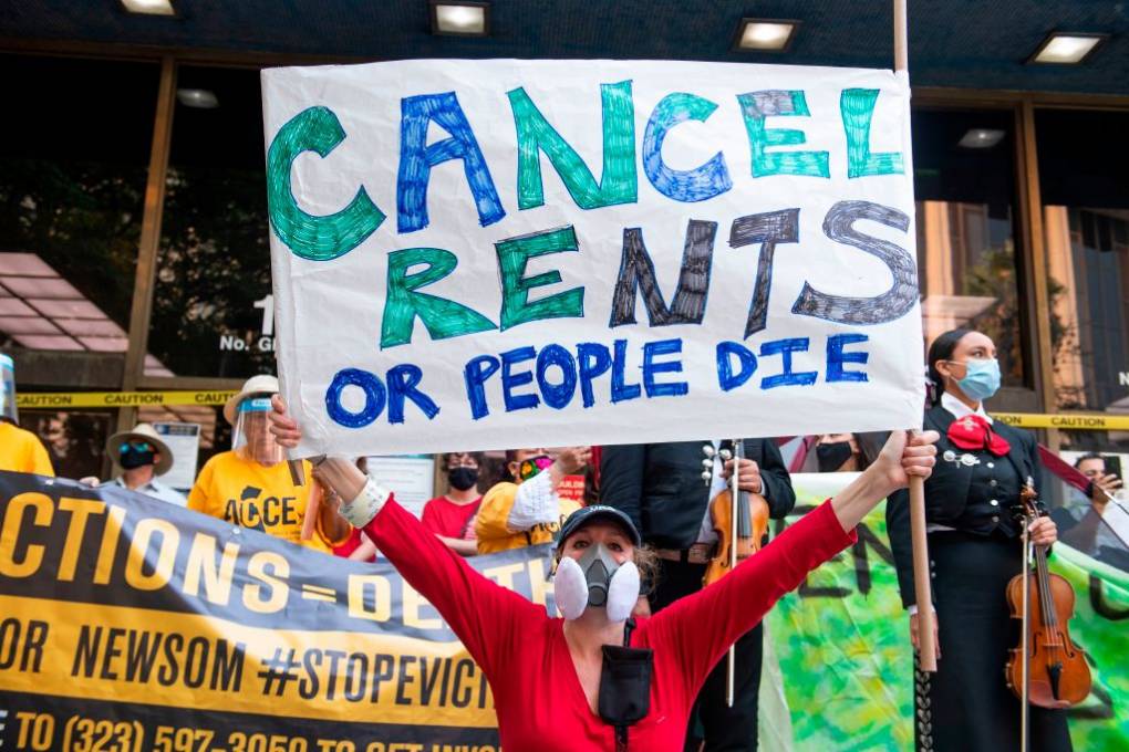 A woman holds up a big sign that says "Cancel Rents of People Die."