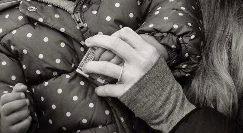 Black and white detail of Mara Reinhardt's hand holding her young daughter's
