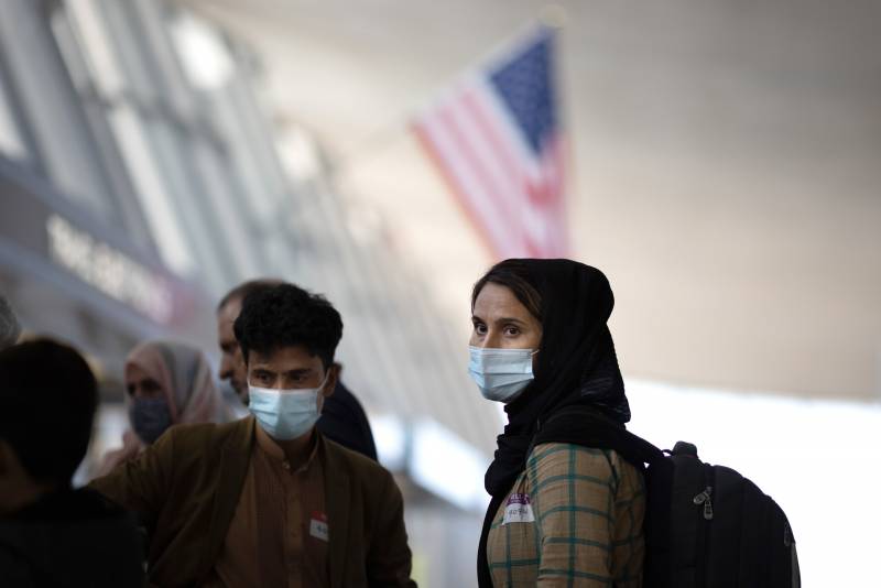 refugees wear masks, head scarves and backpacks inside US airport