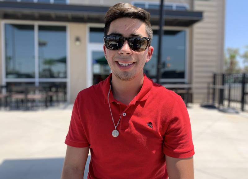 Young man smiling in sunglasses and red polo shirt