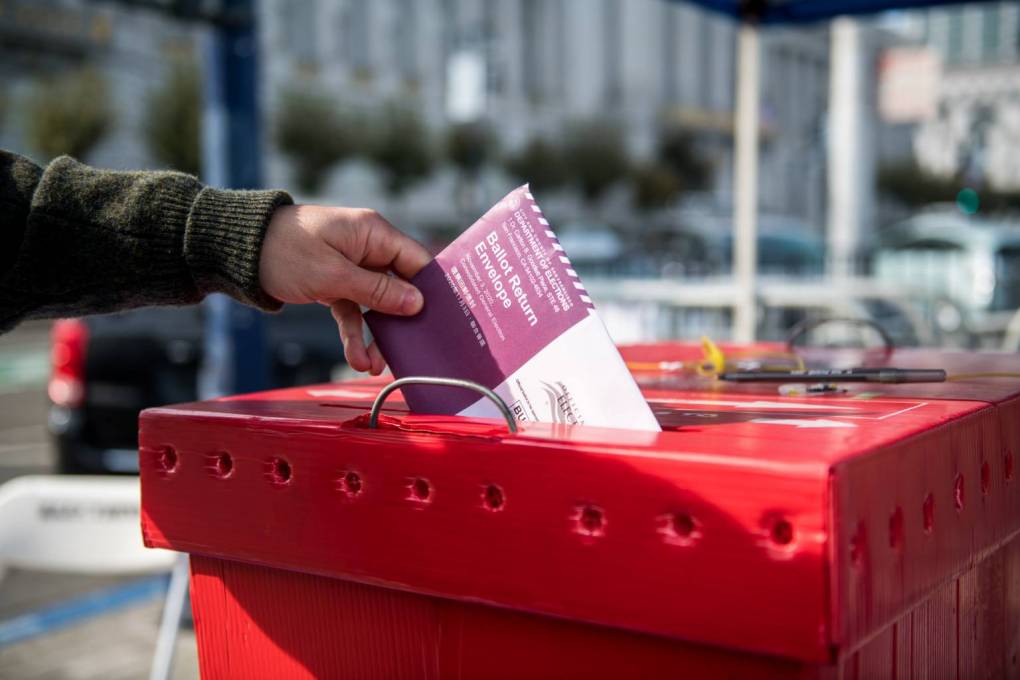 A ballot is placed in a red ballot box.